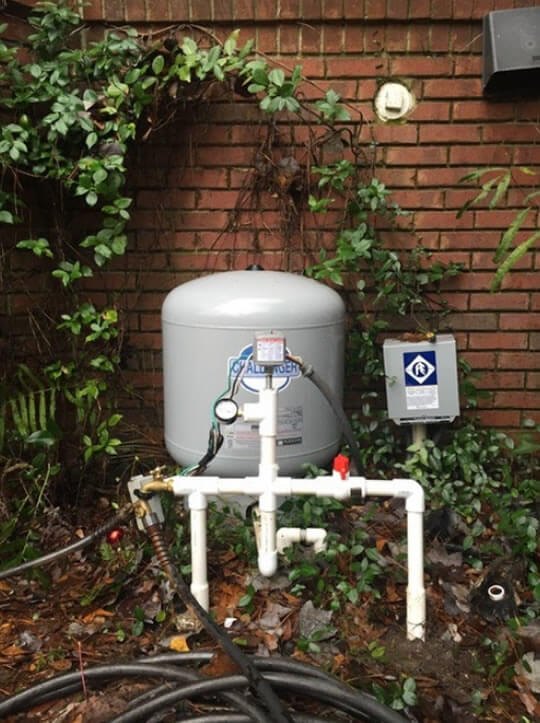 Pressure tank and control box installed against a brick home